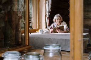 Retired woman sitting at a table reading a book in her new home